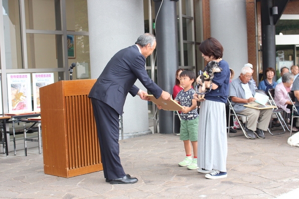 飼い主の男の子が母親と犬と一緒に表彰状をうけとっている写真
