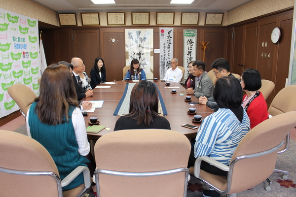 応接室にてチェンマイの方々と市長や職員と椅子に座って談笑する様子の写真（別角度）