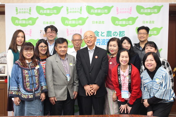 丹波篠山市と書かれた壁の前でチェンマイの方々と市長、職員が笑顔で並んでたっている写真