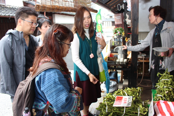 市内店先で黒枝豆を見ながらチェンマイの方々が説明を聞いている様子の写真