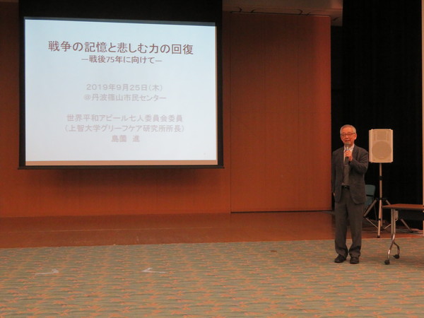 島薗先生がスクリーンの前でマイクを持ち話されている写真