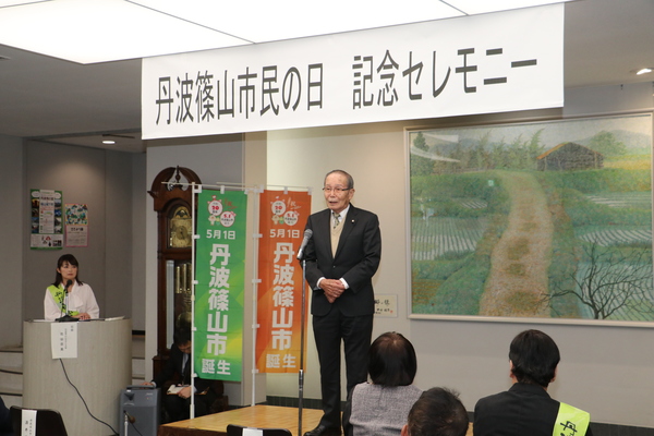 丹波篠山市民の日記念セレモニーと書かれたプレートの下で挨拶をする梶原さんの写真