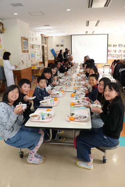 給食甲子園出場メニューをおいしそうに食べる笑顔の子どもたちの写真