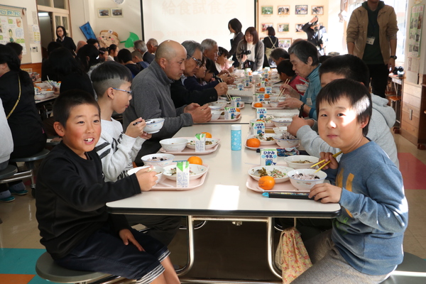給食甲子園出場メニューをおいしそうに食べる笑顔の子どもや大人たちの写真