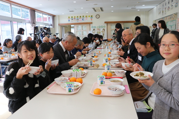 給食甲子園出場メニューをおいしそうに食べている笑顔の子どもや大人たちの写真