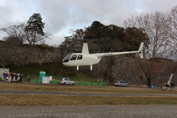 広場から離陸する観光ヘリコプターと遠くで見守る方々の写真