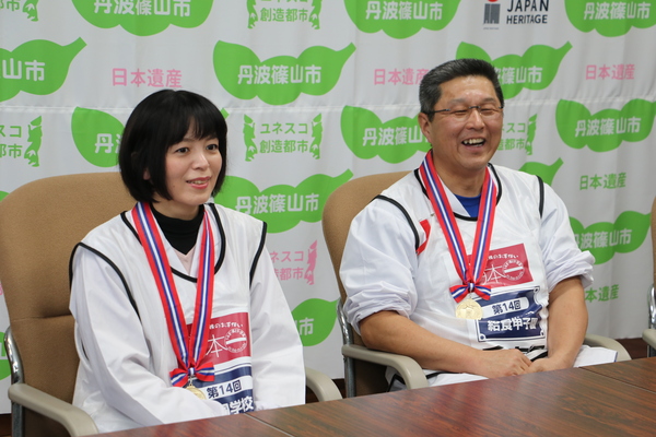 メダルを首にかけ椅子に座り、笑顔で話をしている栄養教諭の田畑さんと調理員の出野さん