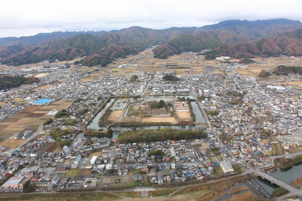 上空からみた、城跡を取り囲む民家や田畑、紅葉した山々の写真