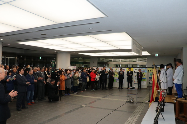 市民ホールにて舞台の給食センター員さんにむけ大勢の職員が拍手をおくっている様子