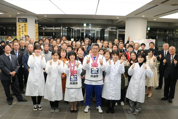 給食センター員の方々はガッツポーズをし、そのまわりを職員が笑顔で取り囲んでいる集合写真