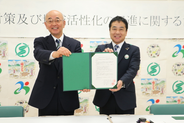 緑色の額縁にはいった文章を一緒に掲げる、美郷町長嘉戸さんと酒井市長