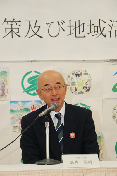 マイクの前で話をするスーツ姿の酒井市長