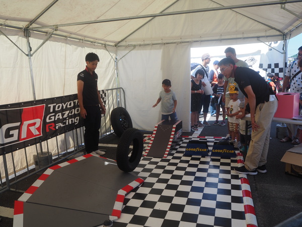 タイヤを転がし子どもと大人が遊んでいる写真