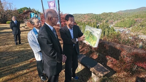 日本大正村ボランティアガイド梅村さんが絵と景色を照らし合わせながら酒井市長へ詳しくご案内している写真