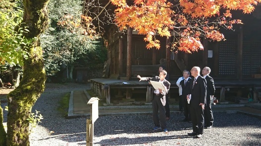 紅葉と大きな楓の木の前で書類をもちながら説明を受ける酒井市長と数人のスーツ姿の男性
