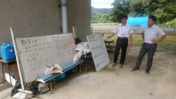 ホワイトボードに書かれた文章について男性二名が説明をしている様子の写真