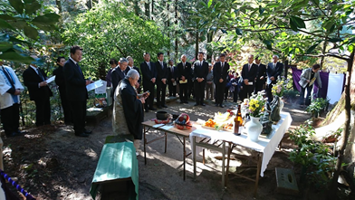 供養台の前に黒いスーツ姿の方々が大勢ならび供養祭がおこなわれている様子