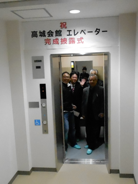 完成エレベーター内で乗り込んだ四名の男性がドアをあけたまま笑顔で立っている写真