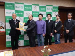 篠山市原子力災害対策検討委員会メンバーと市長がハンドブックを持ち整列している写真