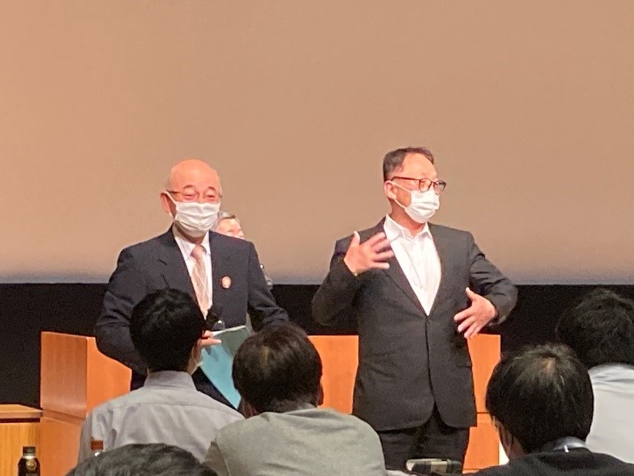 市長と教育長が総会で前に出ている。教育委長が手話でうれしいと伝えている