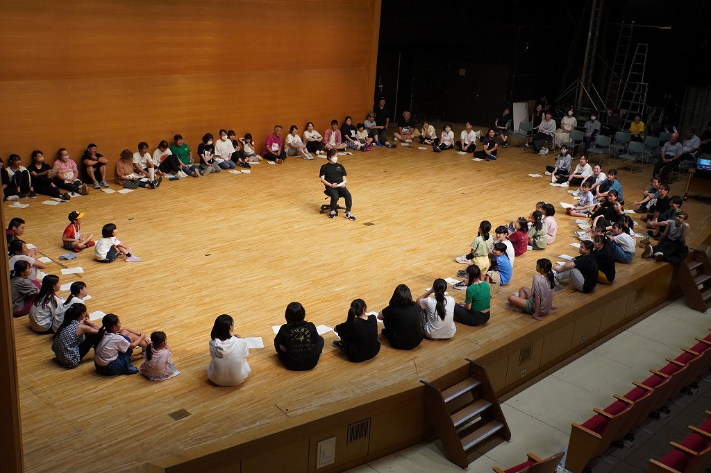 田園ホールの舞台上で円になって顔合わせ会をする出演者や関係者の皆さん