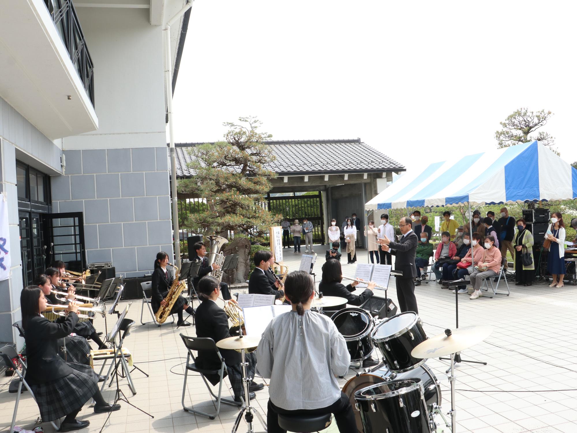 産業高校吹奏楽部の子ども達屋外で演奏している。