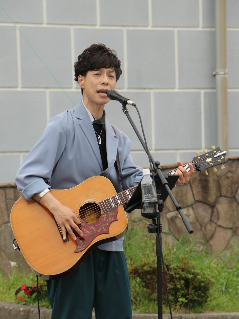 石田裕之さんがギターを弾きながら歌っている