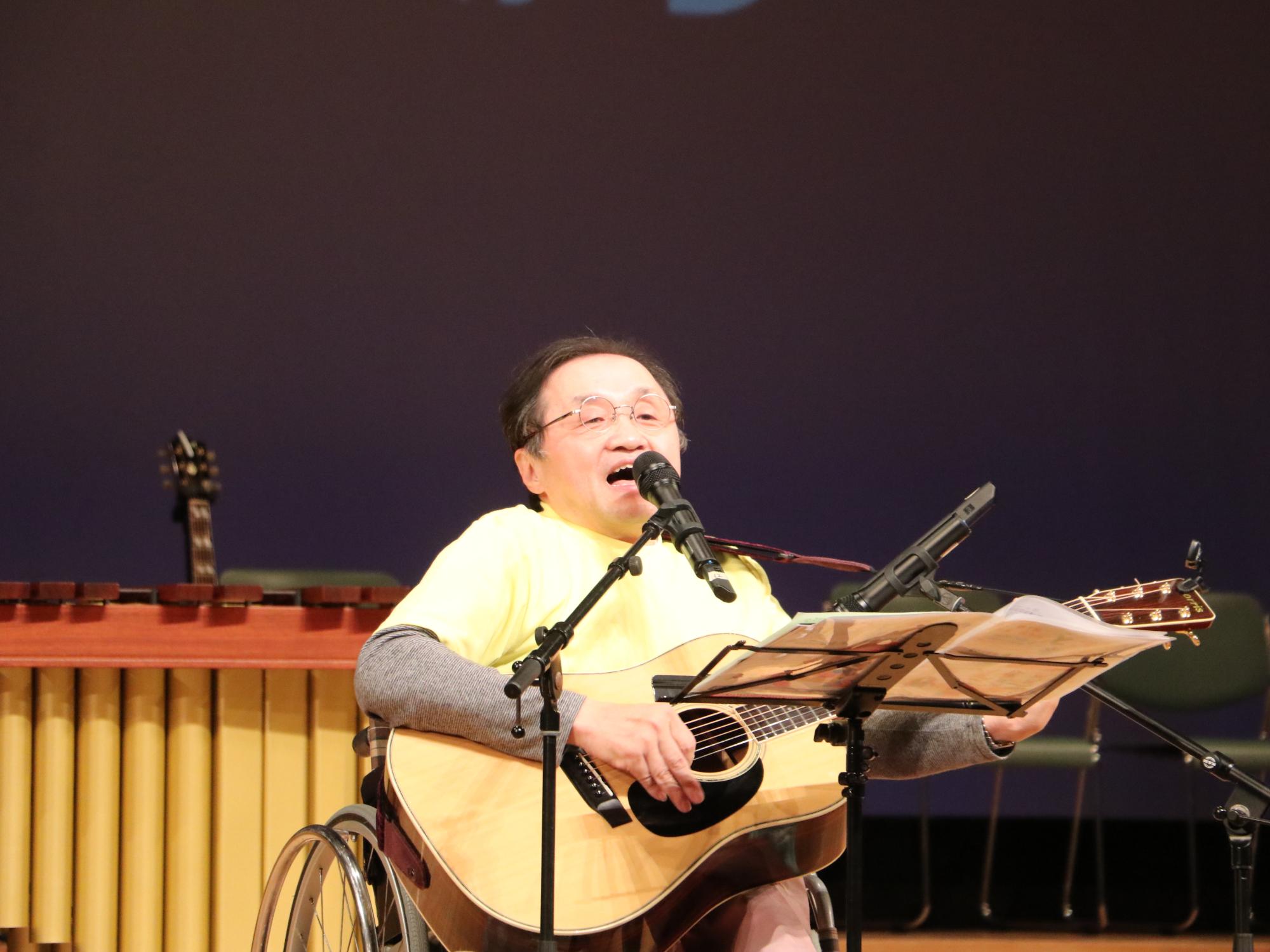 小西実行委員長がギターを弾きながら歌っている