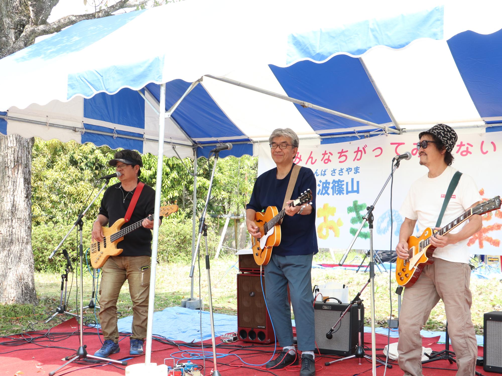 ギターを弾きながら男性3人が歌っている