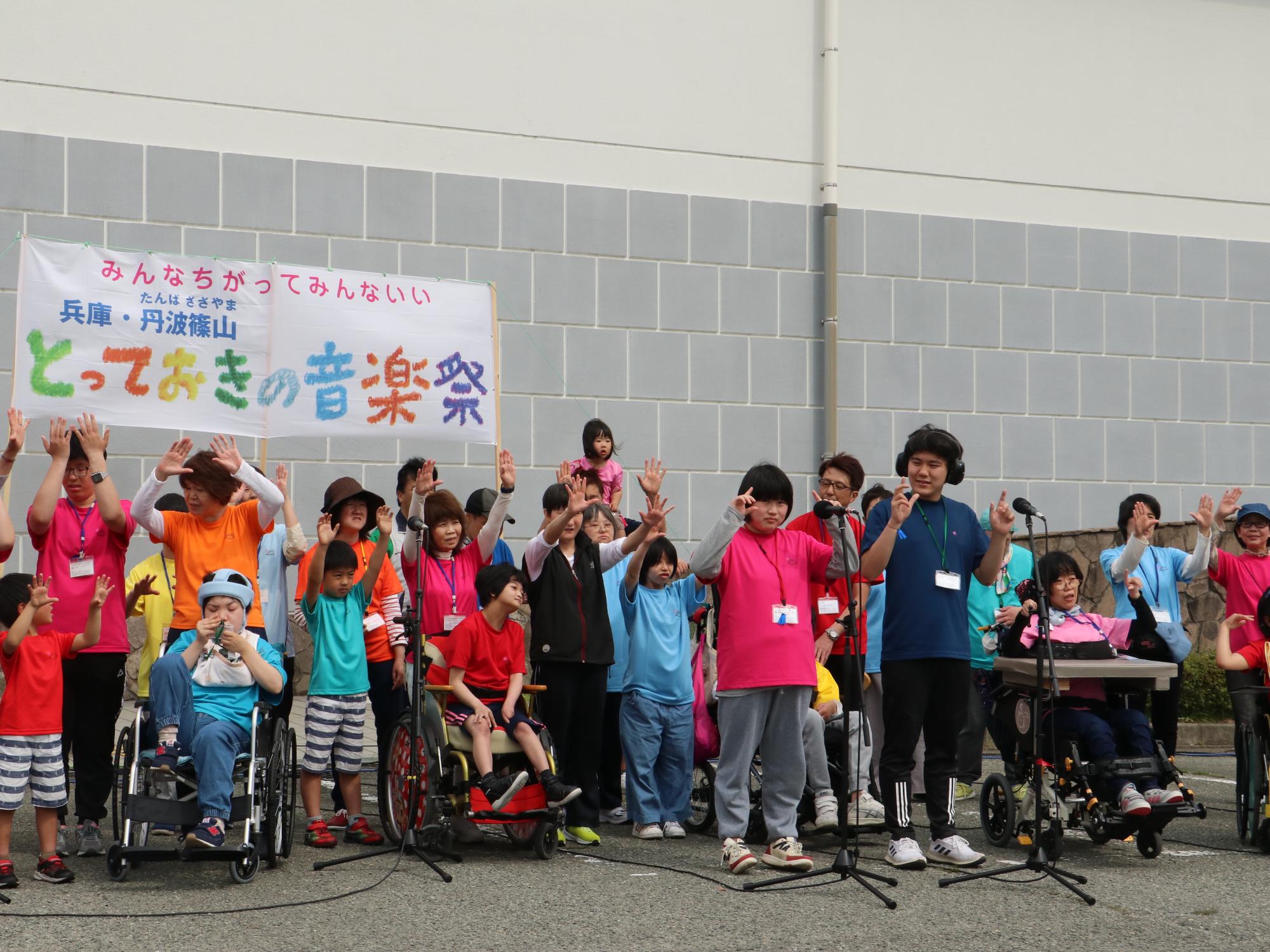 車いすに乗った方も参加してこどもたちや大人が両手をあげている