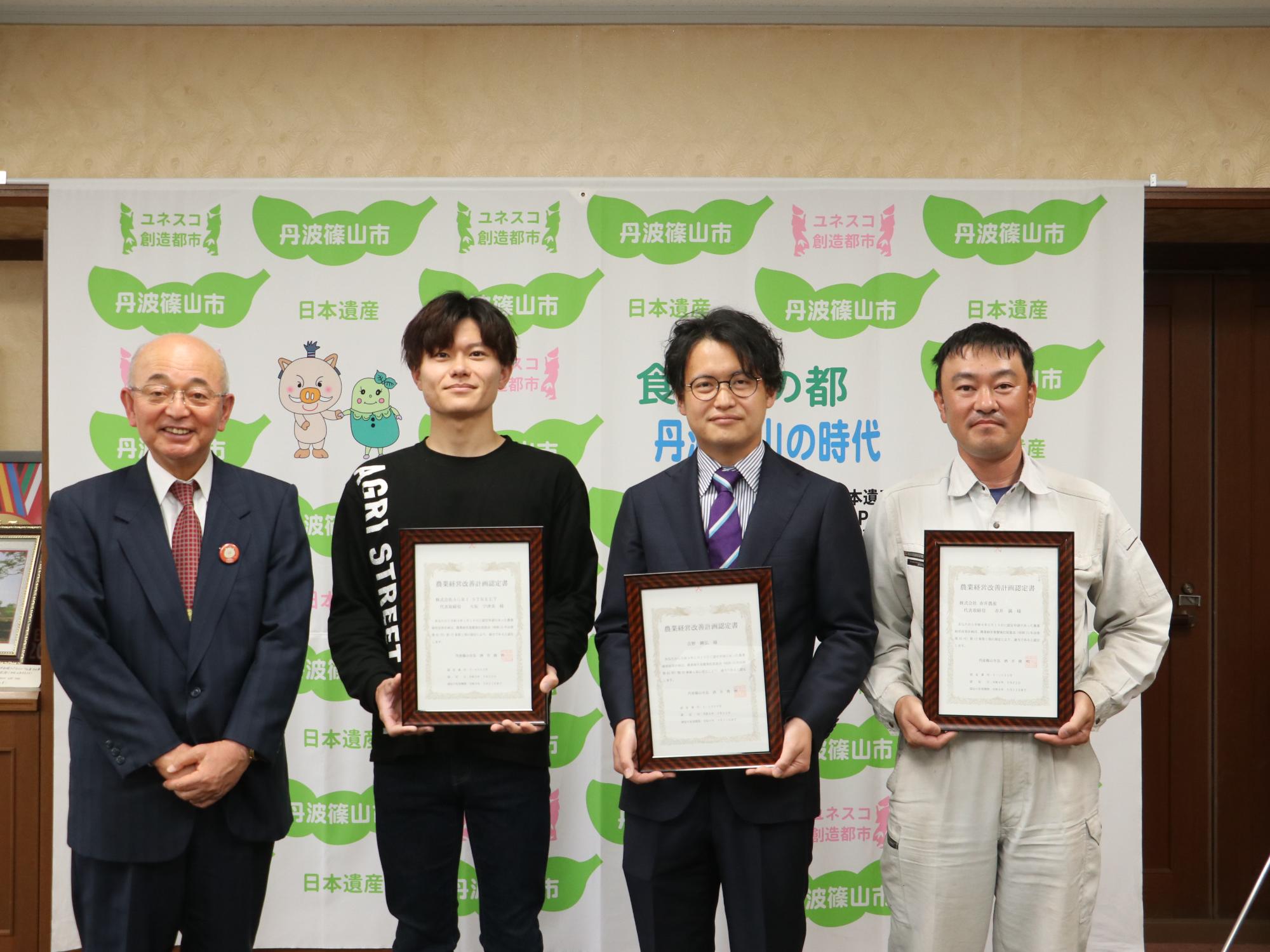認定証を持った男性3人と市長の記念撮影