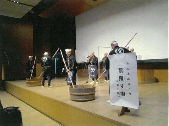 舞台で丹波杜氏の方が法被を着て酒造り唄を披露している