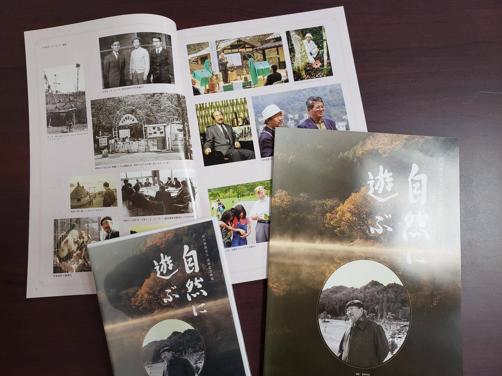 河合雅雄先生の追悼映像DVDと追悼記念誌の表紙と写真が掲載されているページが開いて机に置いてある