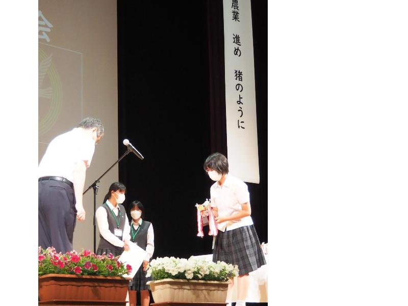 制服を着た女生徒がカップをもらっている