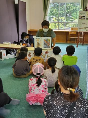 男の人が図鑑を開いて子ども達に読み聞かせを行っている