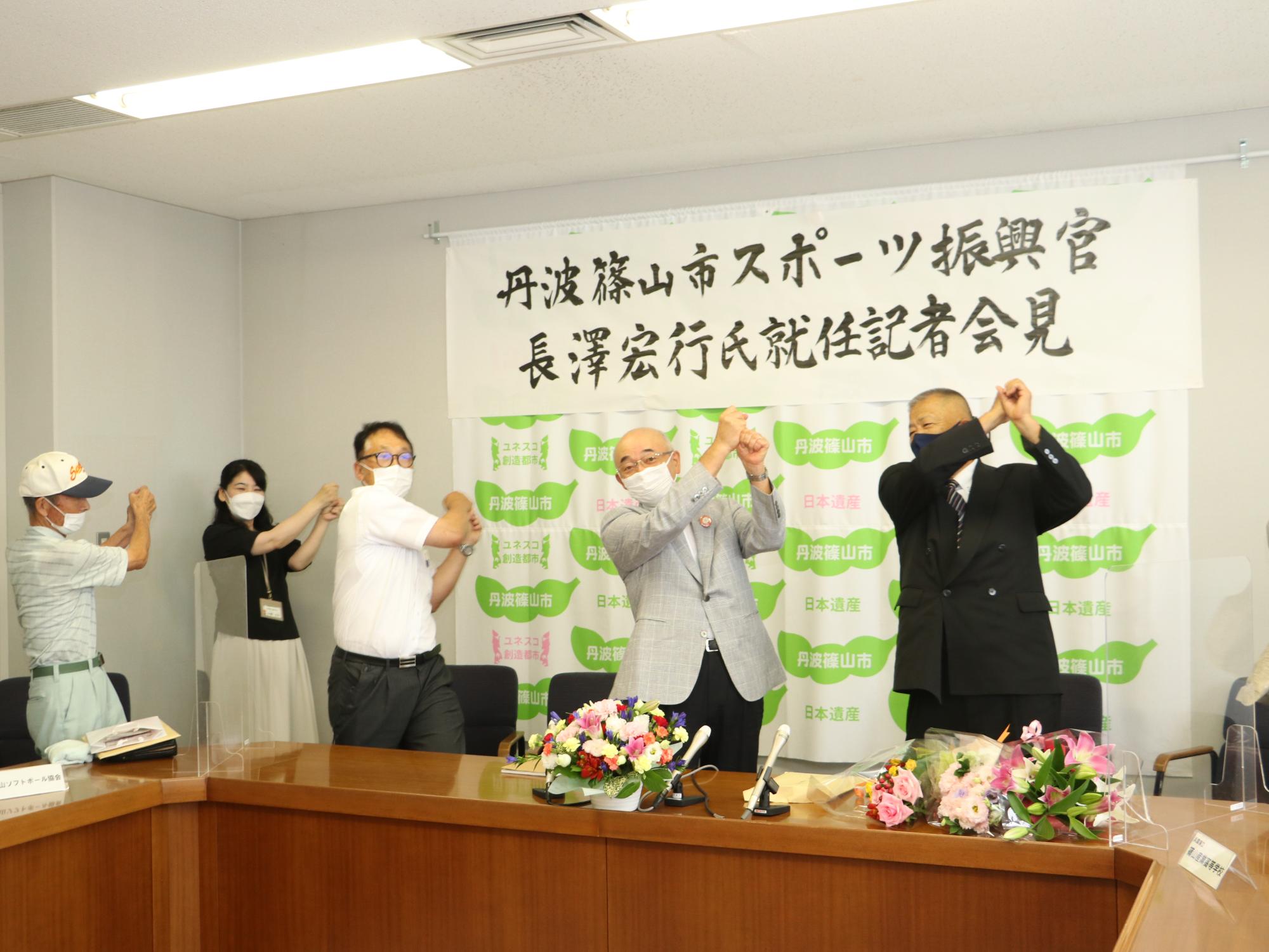 教育長や市長、長沢先生、関係者の皆さんで、バットを振る真似をしている