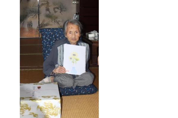 ご長寿の方が、ご自身で描かれた絵を手に持っている