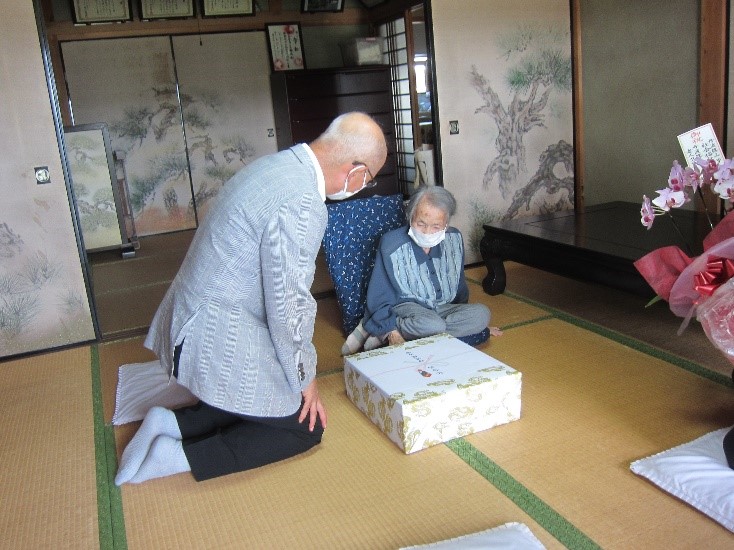市長がご長寿の方にお祝いの品を渡している