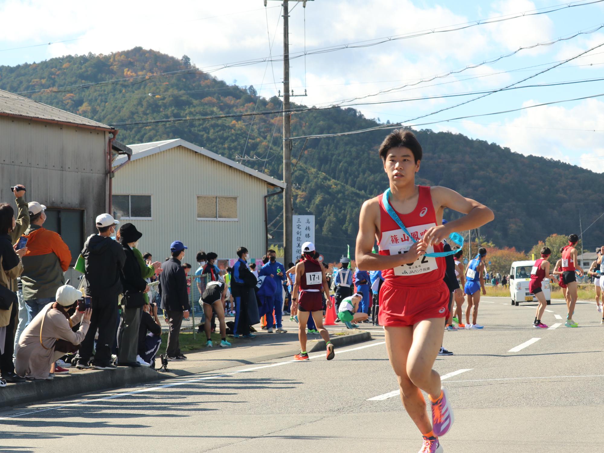 駅伝で2区のランナーがたすきをもらって走り出している