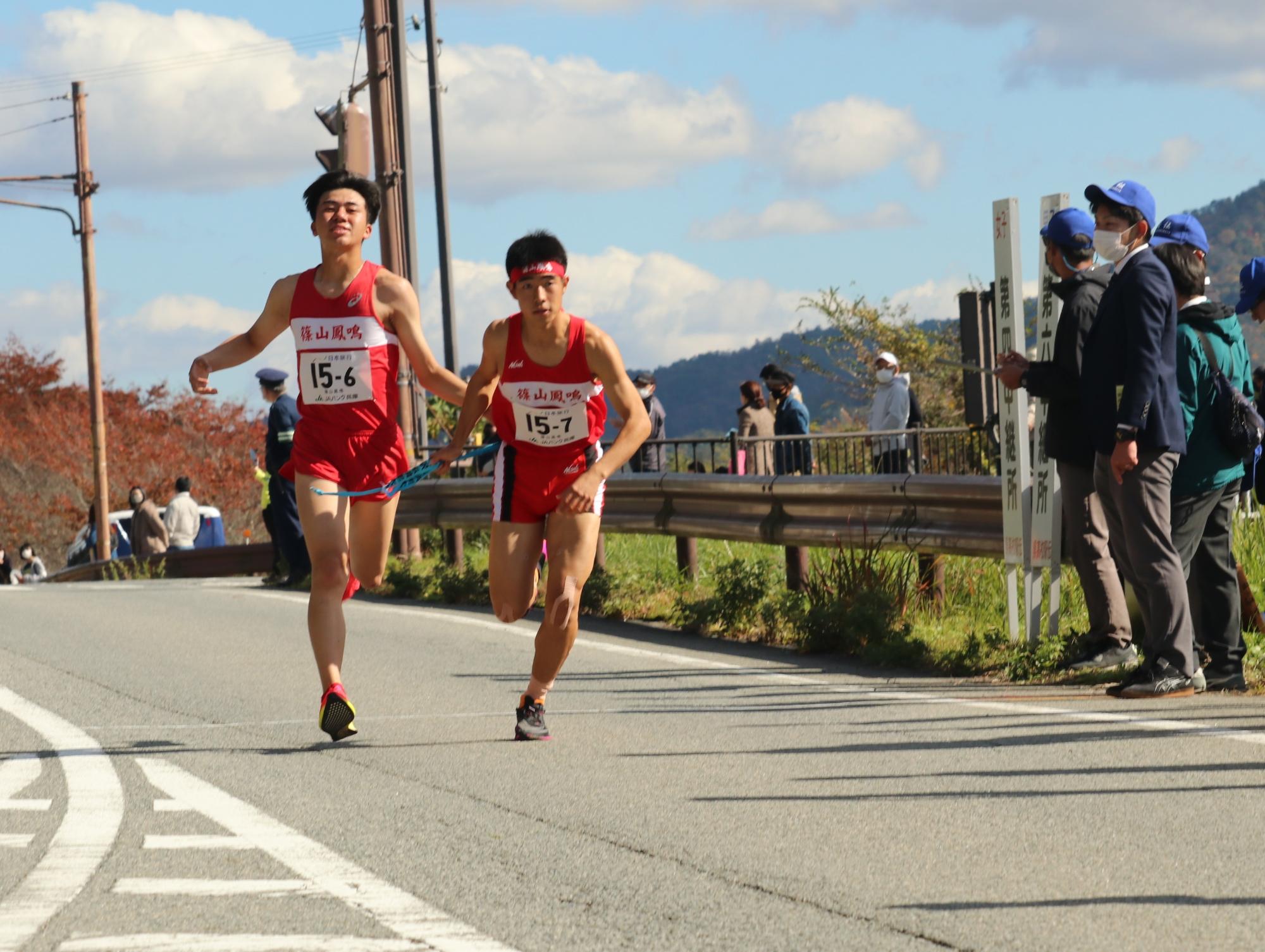 駅伝で6区のランナーが7区のランナーにタスキを渡している