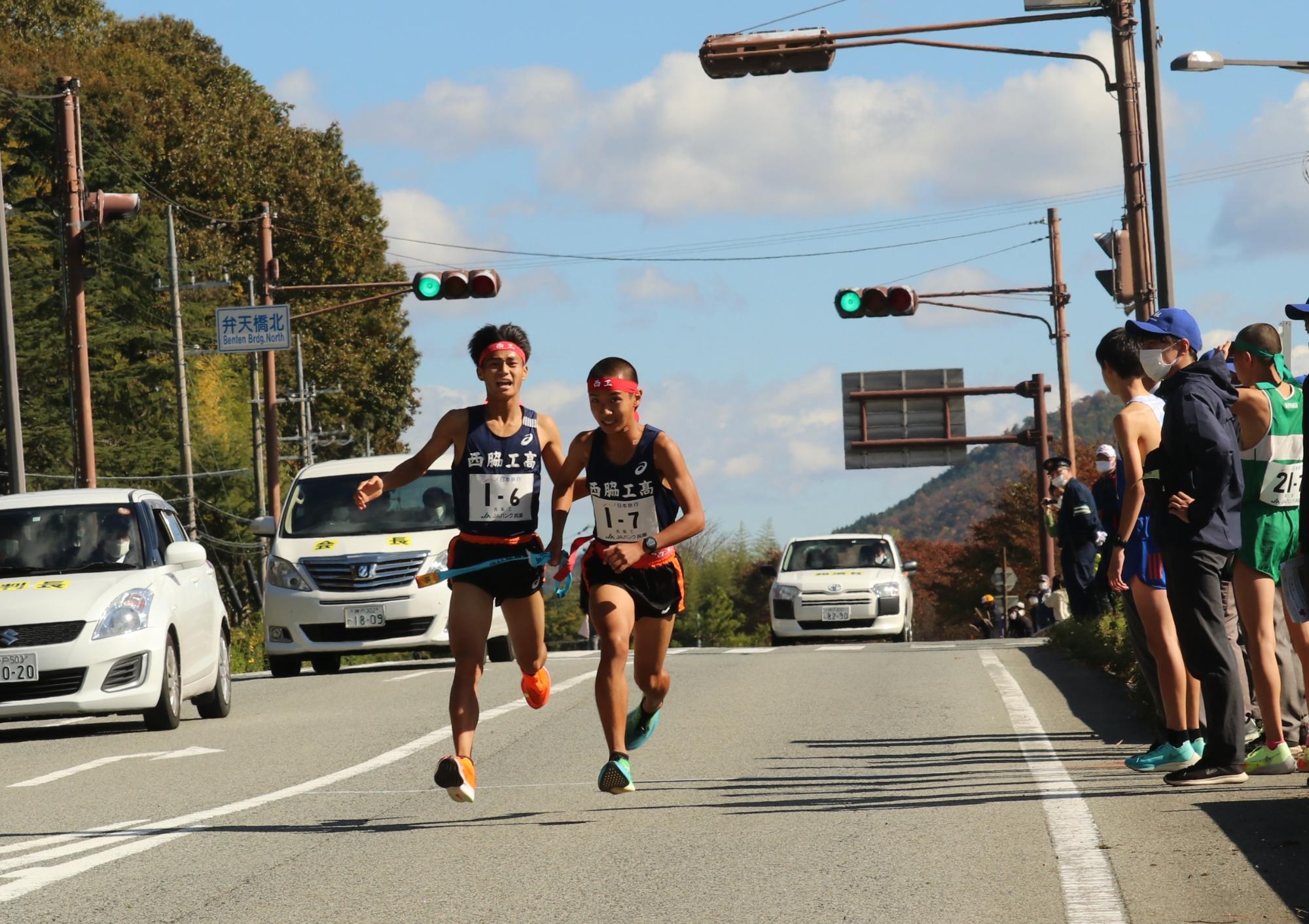 駅伝で6区のランナーが7区のランナーにタスキを渡している