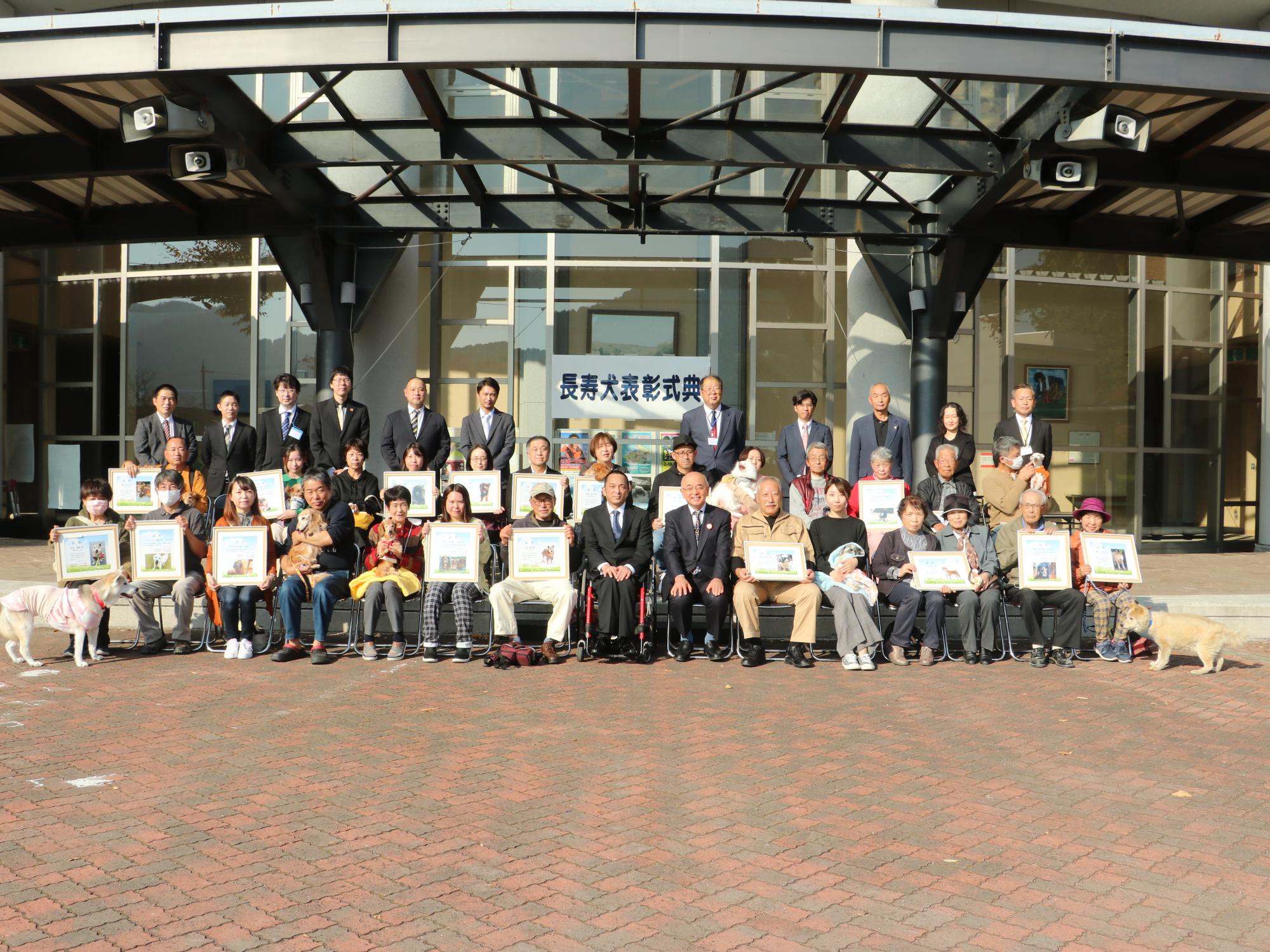 長寿犬の表彰式で飼い主が犬を抱っこしている