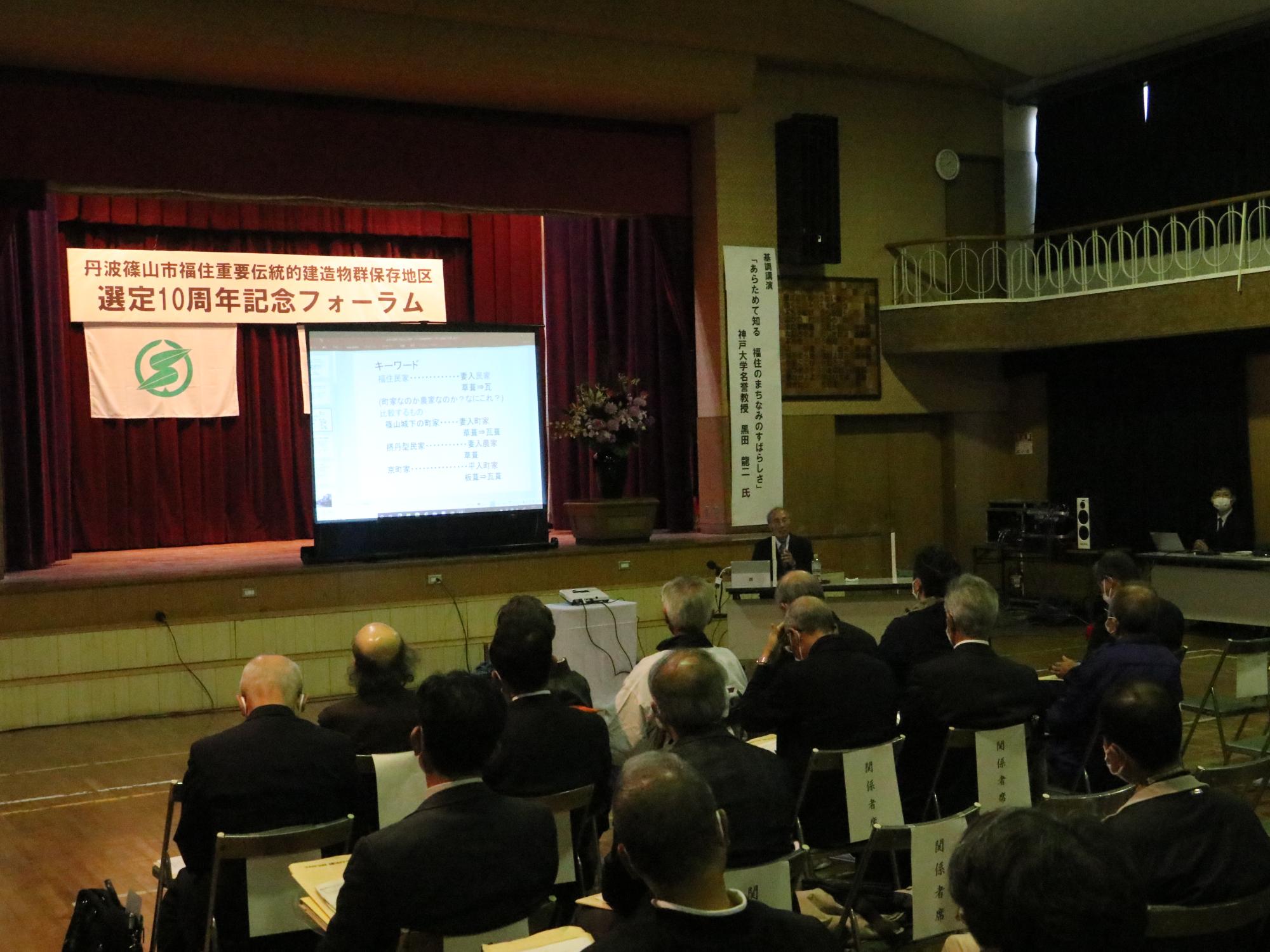 体育館でスライドを使って講演されている