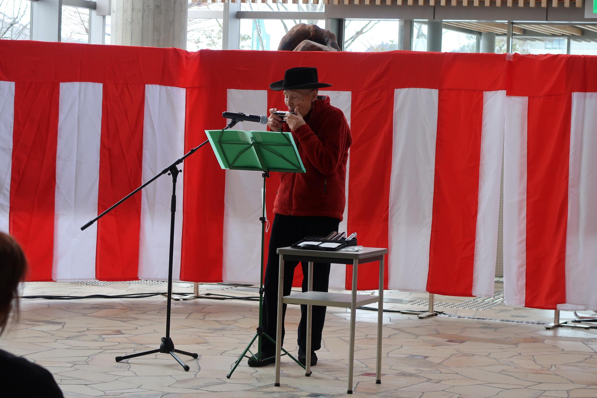 イベントのステージでハーモニカの演奏を披露している