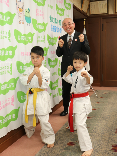 市長と男の子2人が空手の形をしている