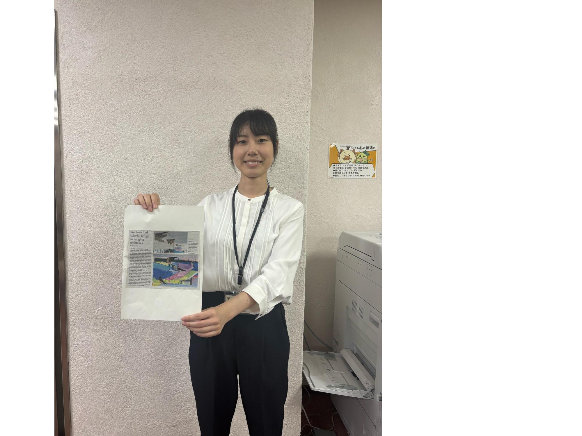 英字版の読売新聞を手に持つ市職員