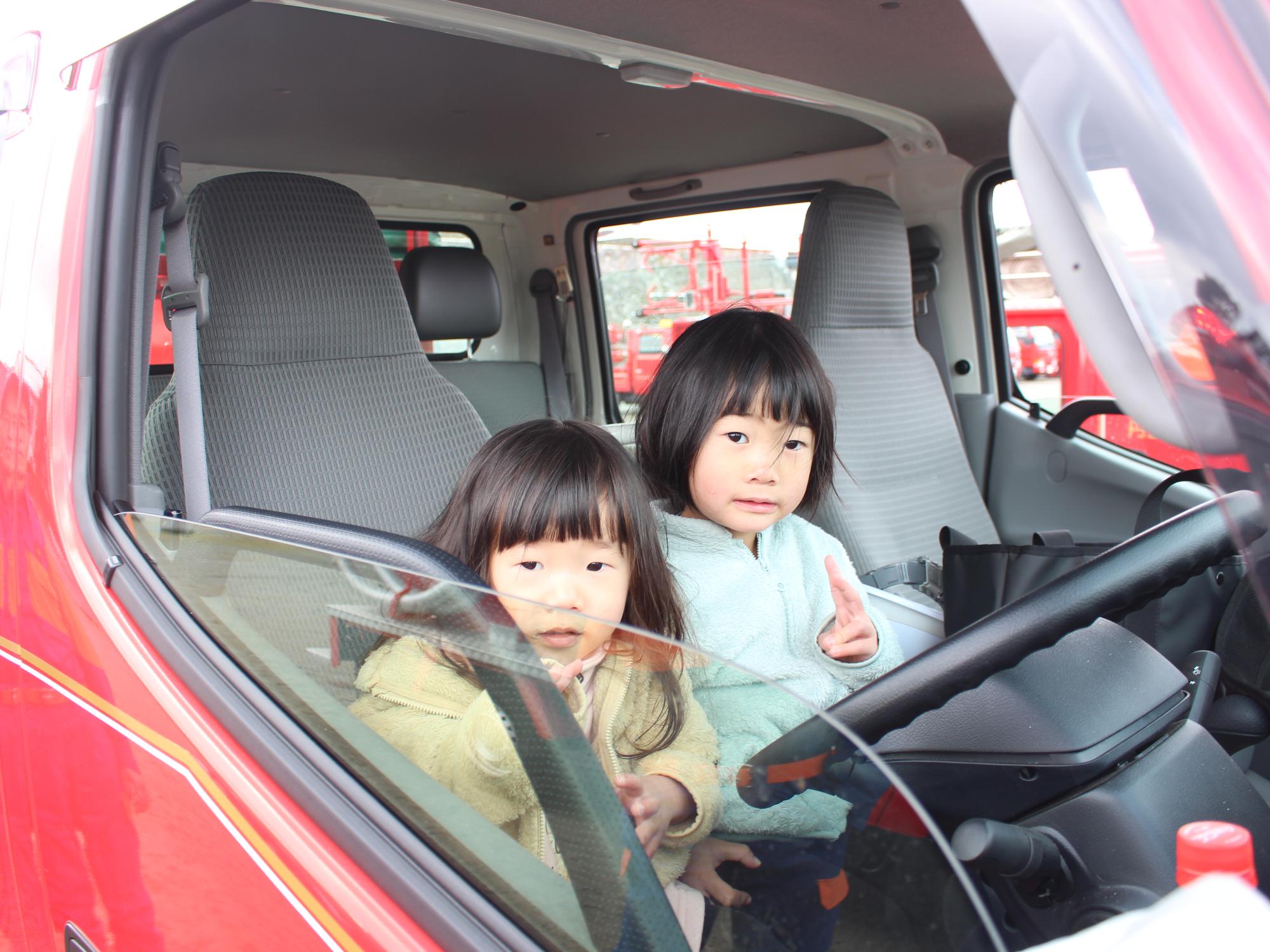 消防車の運転席に乗って写真を撮るこどもたち