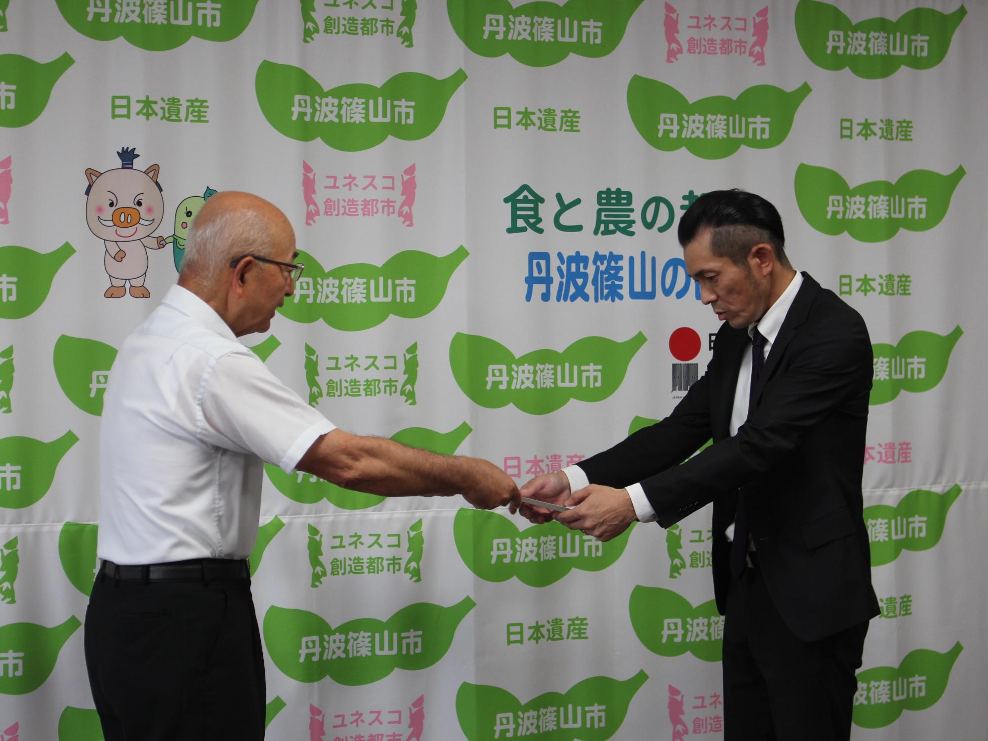 農業経営改善計画認定書を市長から受け取る合同会社よしだ農園代表の吉田啓記さん