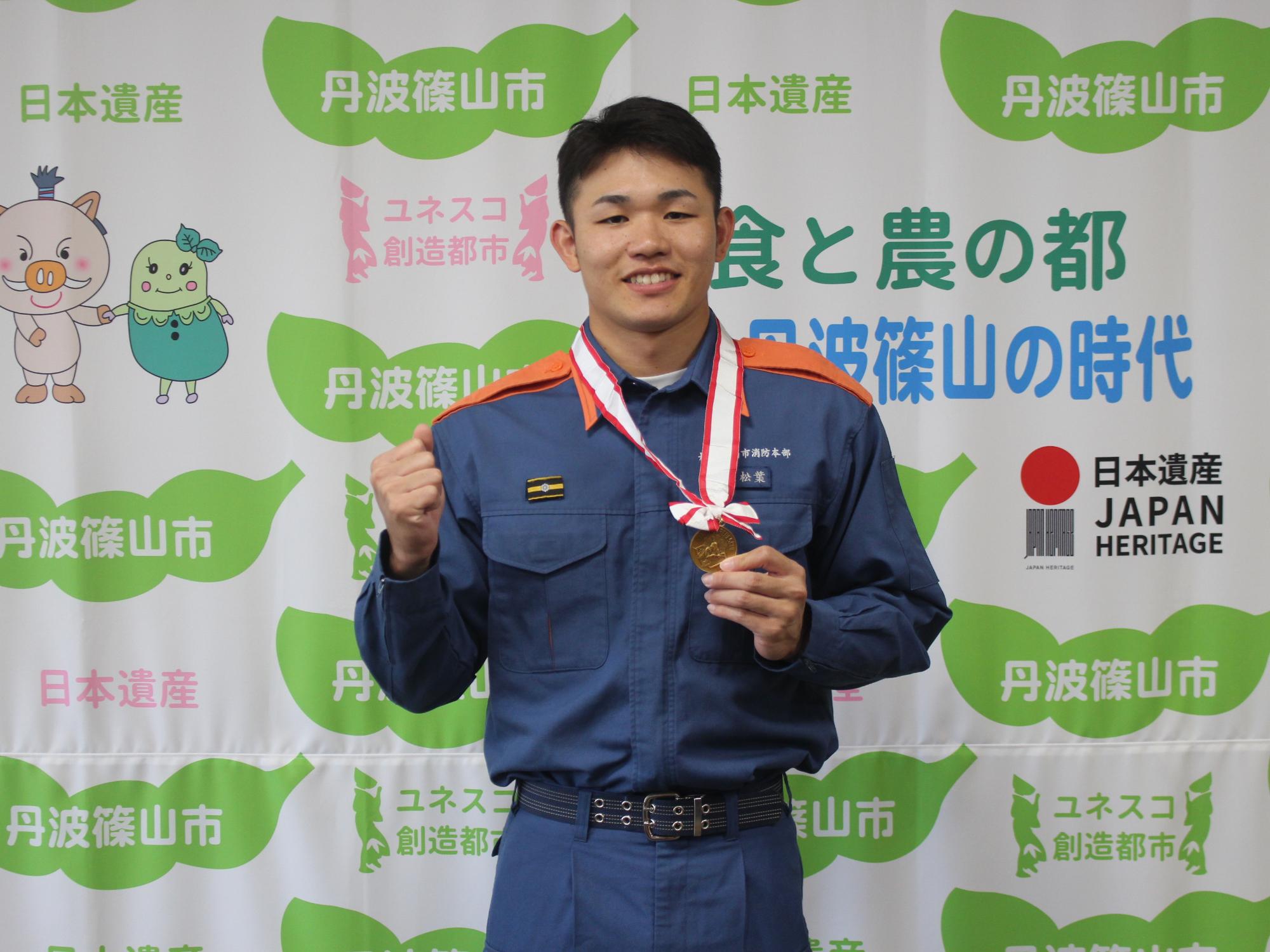 メダルを持ち、ガッツポーズをする松葉さん