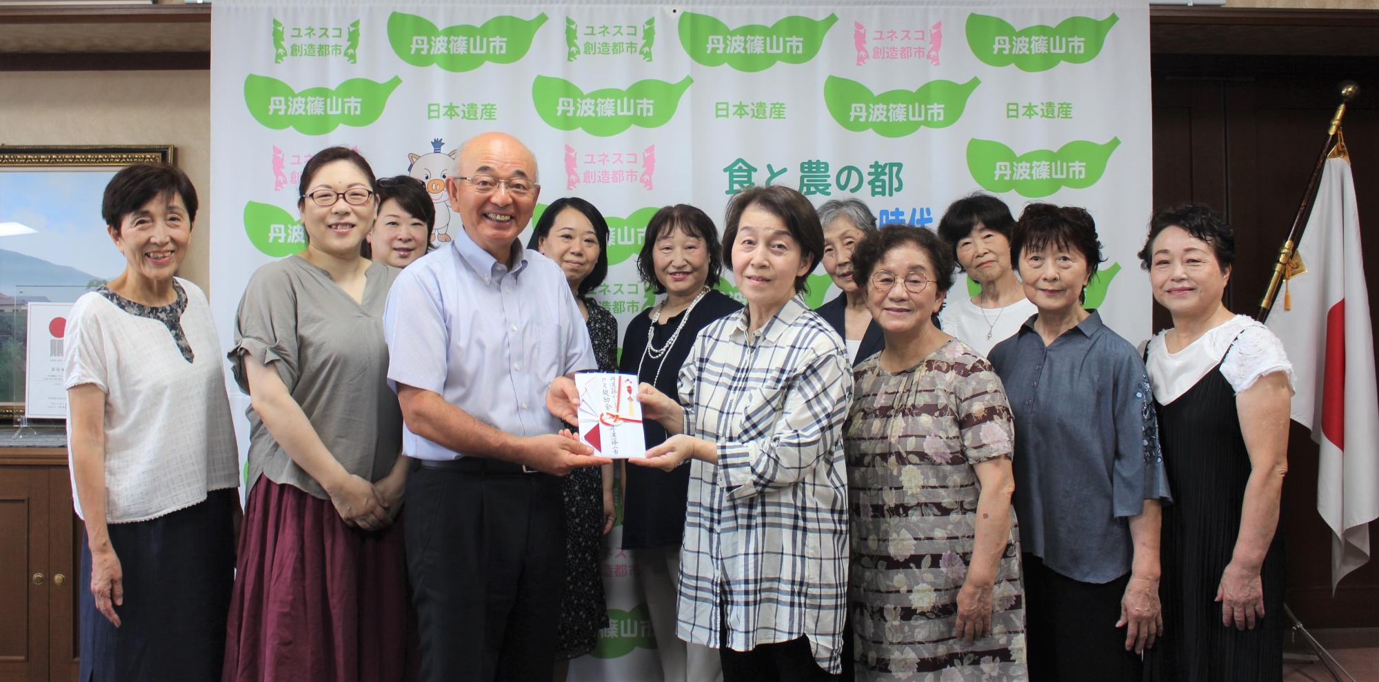 PR奨励金をお渡しする市長と受け取るコーラス・レヴールの皆さん